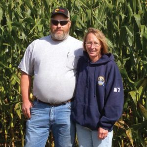 Photo of Randy and Traci Balthaser in front of a cornfield.