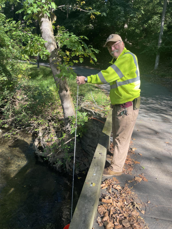 Bob Bardsley collects a water sample from West Branch Chester Creek.
