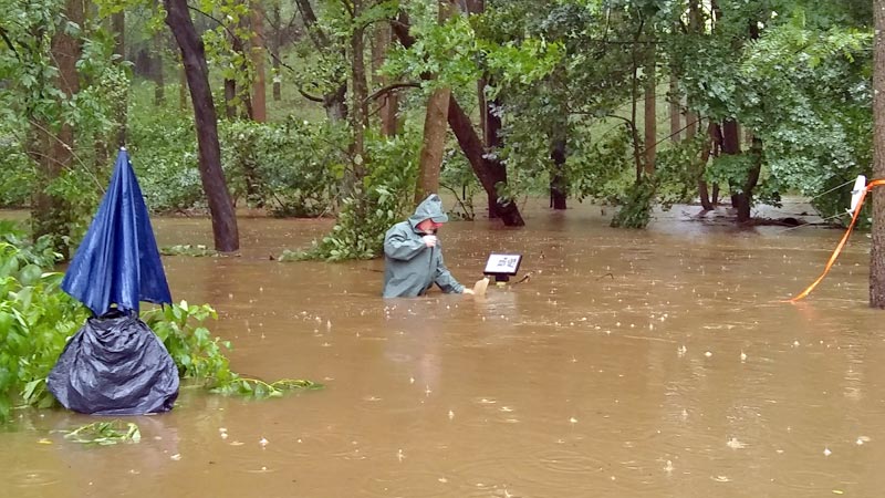 Dave Montgomery collecting a water sample from White Clay Creek during Hurricane Isaias in August to measure the amount of sediment transported during a major flood.