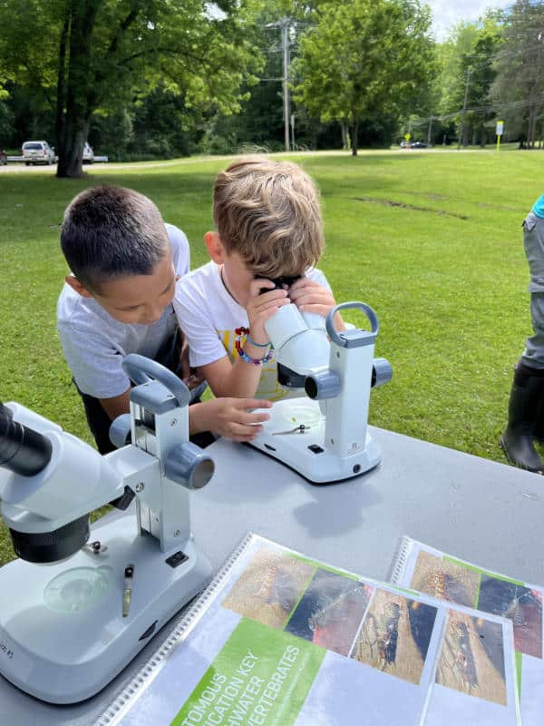 Two boy look through a microscope at a Seneca Nation summer camp.