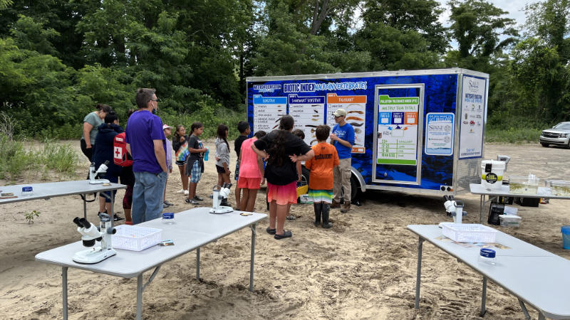 A group of children with the mobile watershed education lab at a Seneca Nation summer camp.