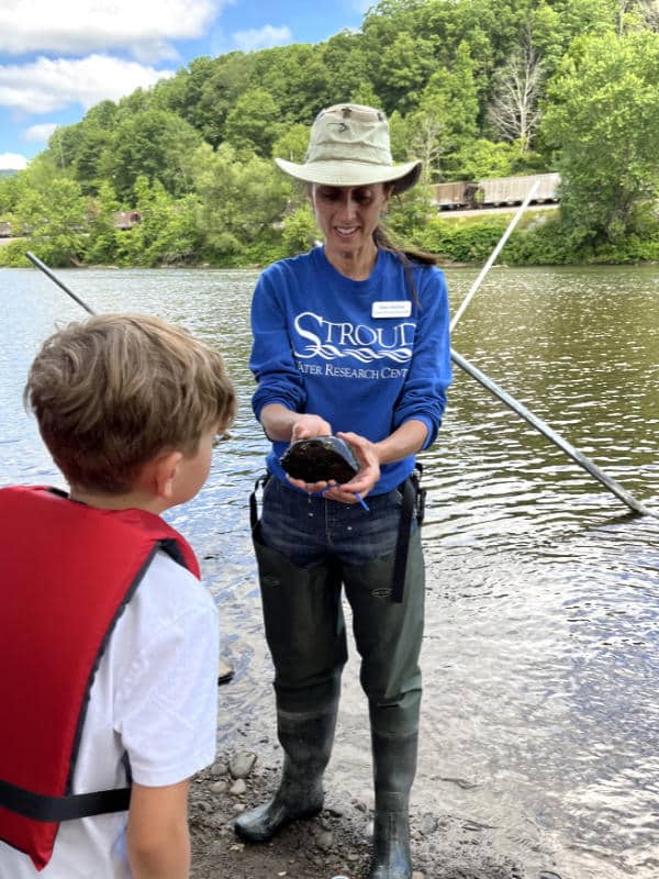 Tara Muenz shows a freshwater turtle to a child at a Seneca Nation summer camp.