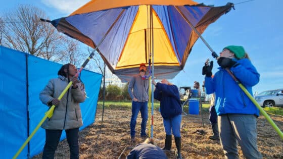 A group of scientist set up the canopy and water supply for a rainfall simulation experiment.