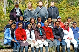 A group of Spanish-language Leaf Pack Ambassador sit on a bridge over White Clay Creek.