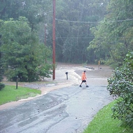 Photo of a person crossing a flooded road