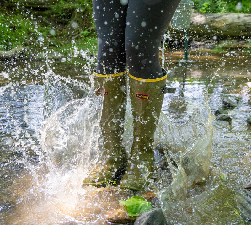 A person wearing boots splashes in a stream.