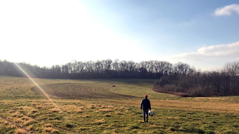 A researcher walking across a field at the Stroud Preserve.