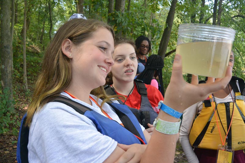 High school students looking at their water sample in an outdoor classroom