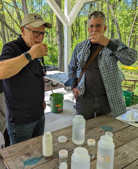 Two men taste water samples that replicate salty streams.