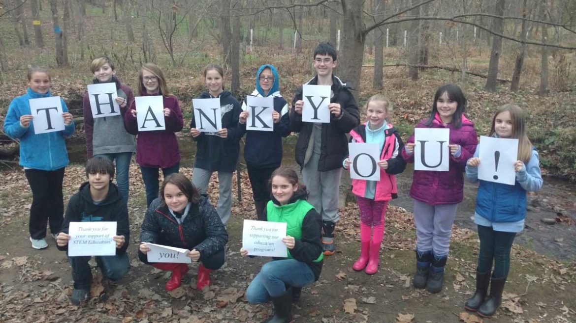 Children holding sheets of paper that spell thank you.