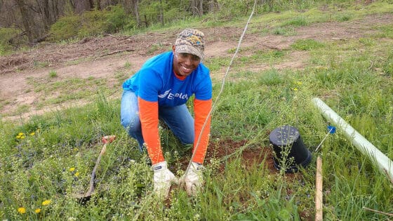 A volunteer from Exelon plants a tree in a new riparian buffer.