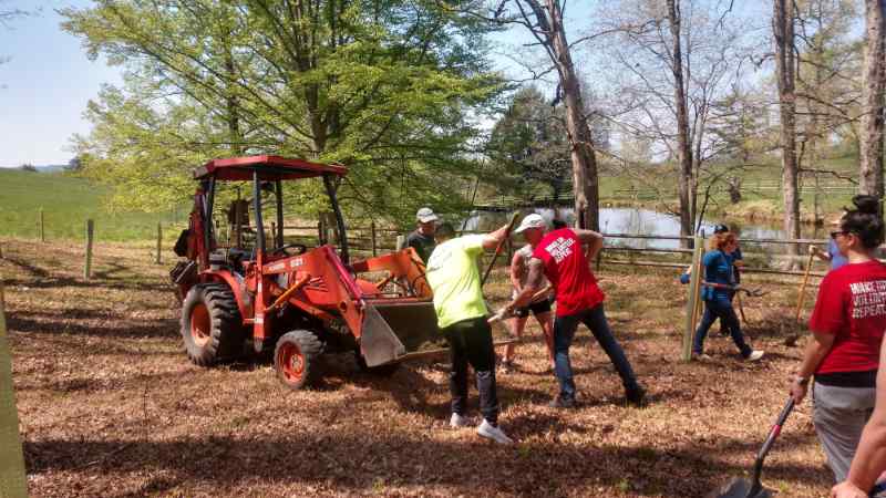 Volunteers shovel mulch around newly planted trees.