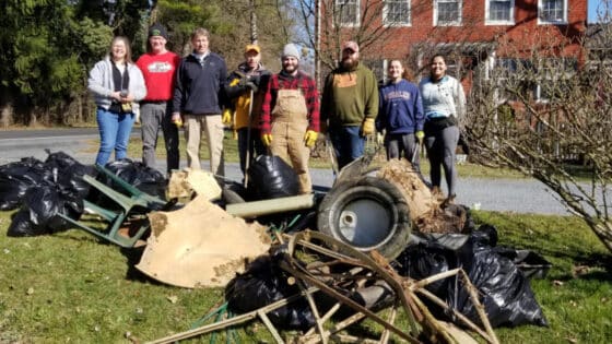 Eight watershed stewards stand behind a large pile of garbage they have removed from a stream.